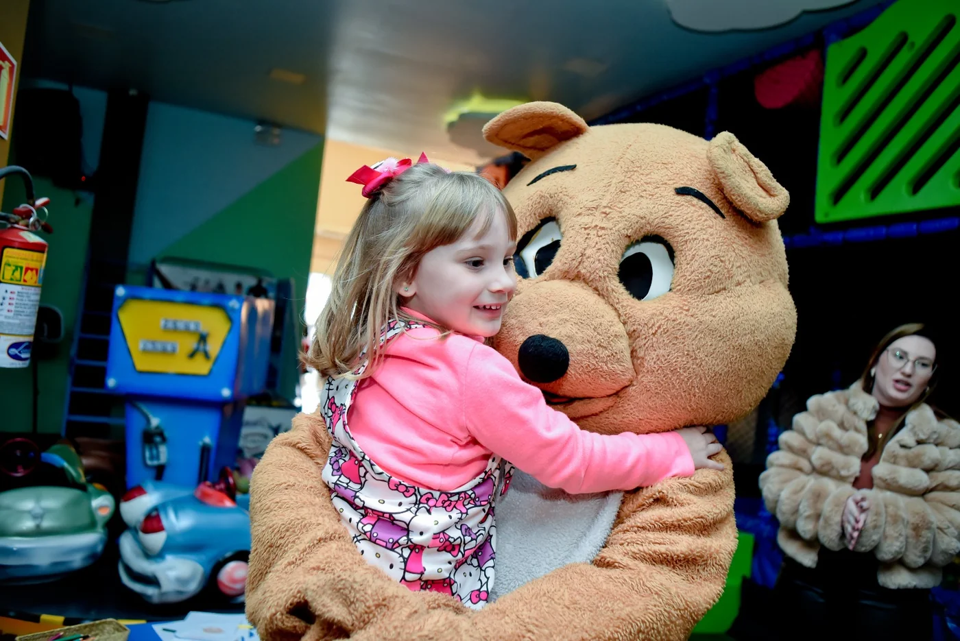 Menina abraçando o mascote Pimpão durante festa infantil