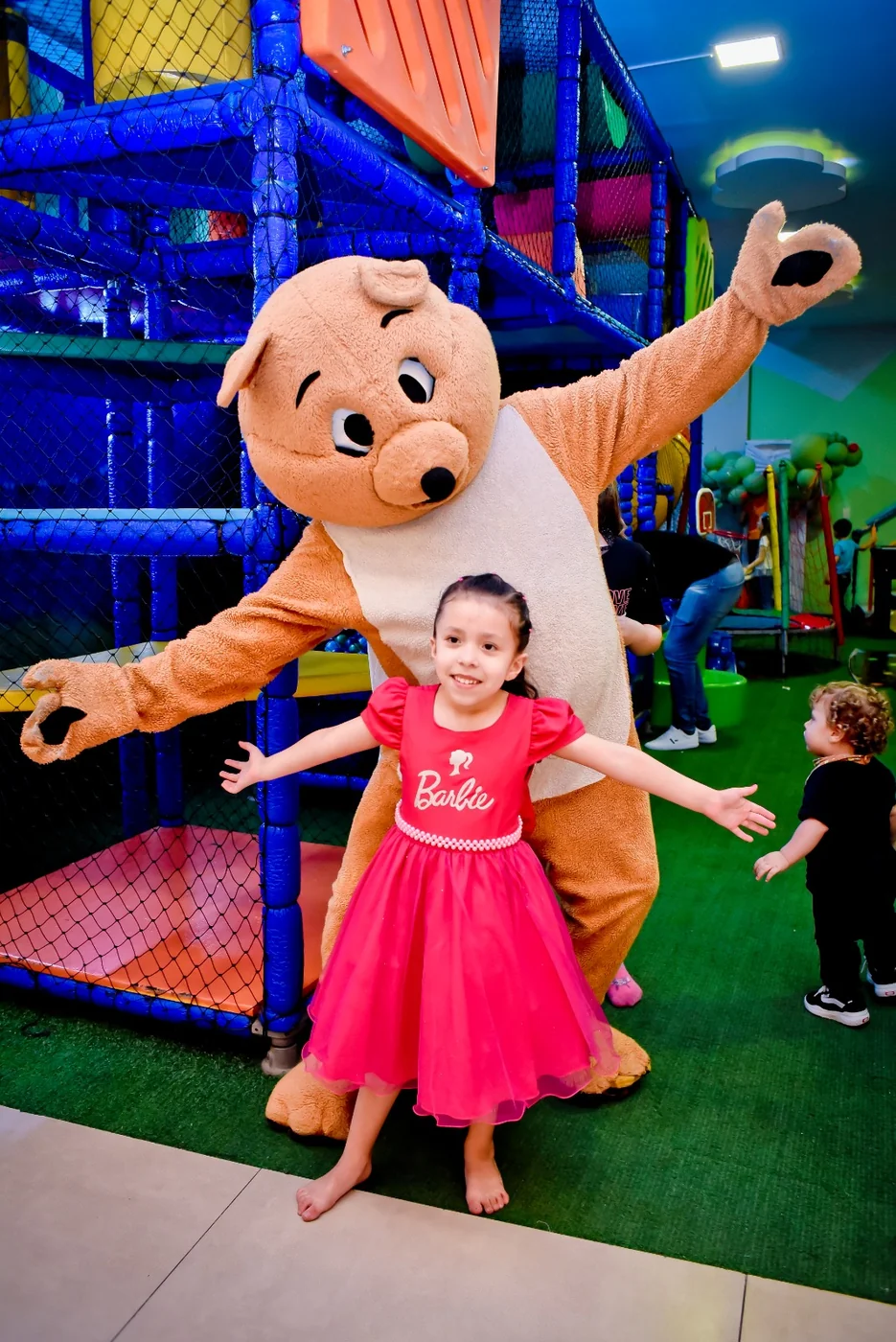 Aniversariante com vestido temático ao lado do mascote Pimpão no playground